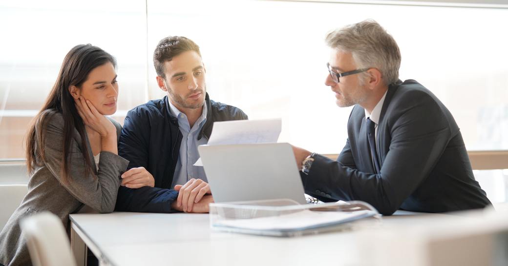 A young couple in a meeting with a professional man looking at a document