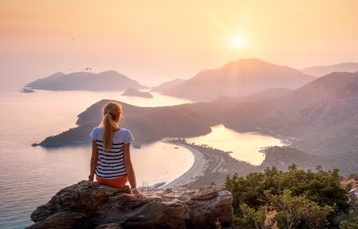 A girl looks out over the islands of Fethiye in Turkey at sunset