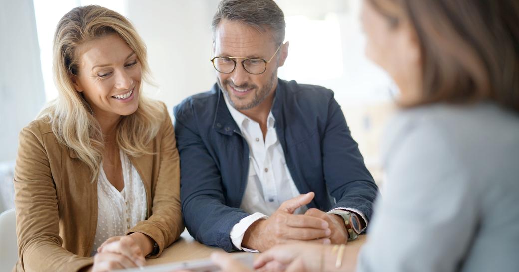 A couple in a meeting with a professional woman pointing to a document