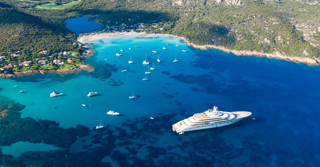 View from above, stunning aerial view of the Grande Pevero beach with boats and luxury yachts sailing on a turquoise, clear water. Sardinia, Italy.